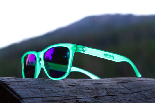 pair of green sunglasses sitting on a log