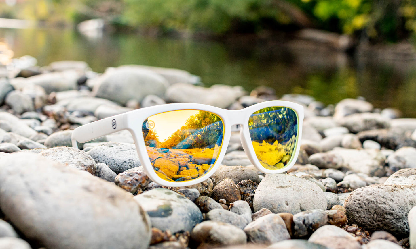 closeup of white sunglasses sitting next to a river